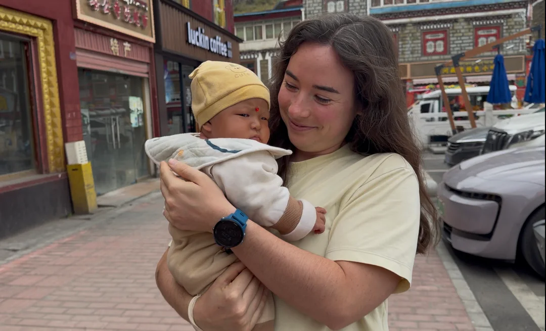 Eva smiling down at a three-month-old local baby in her arms