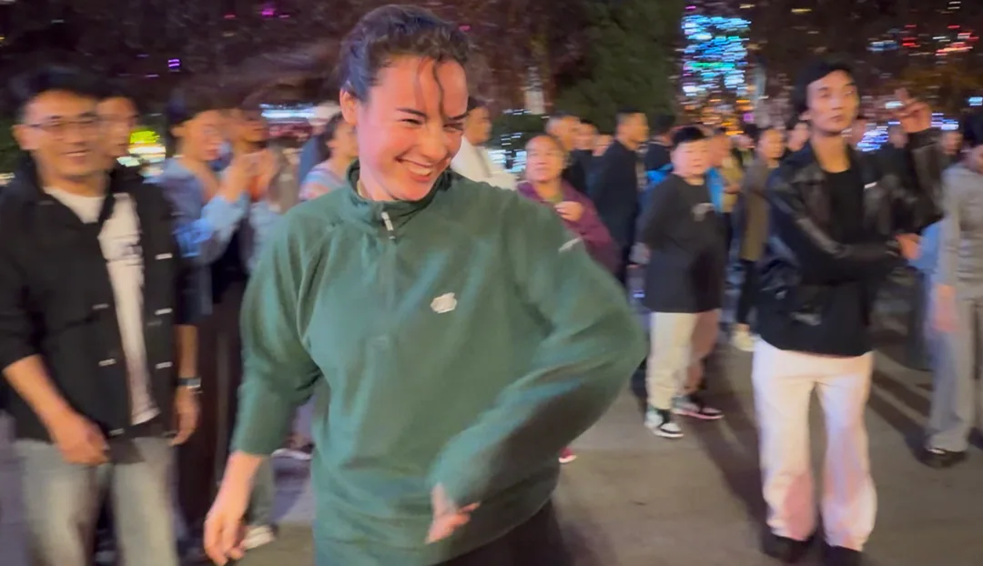 Eva laughing as she joins the dance circle in Kangding at night